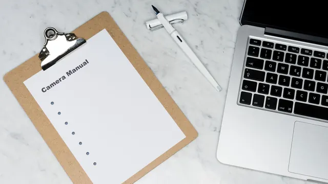 Clipboard, pen and laptop on a marble desk
