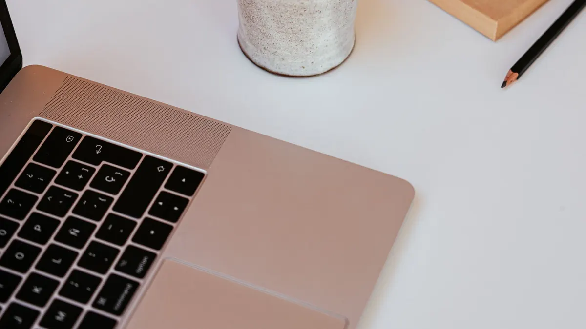Laptop on a white desk beside a notepad and a pencil