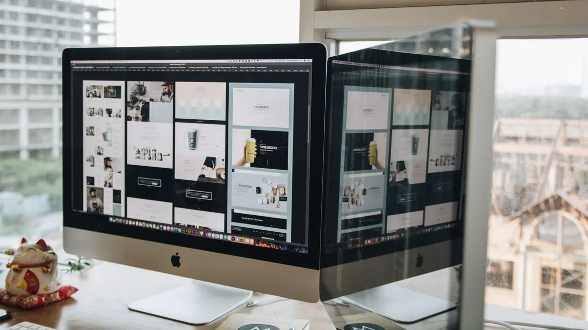 Two desktop monitors on a desk showing web design work